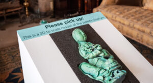 Internal sign asking visitors to "Please pick up" the 3d, scale model of the Jadeite Guanyin