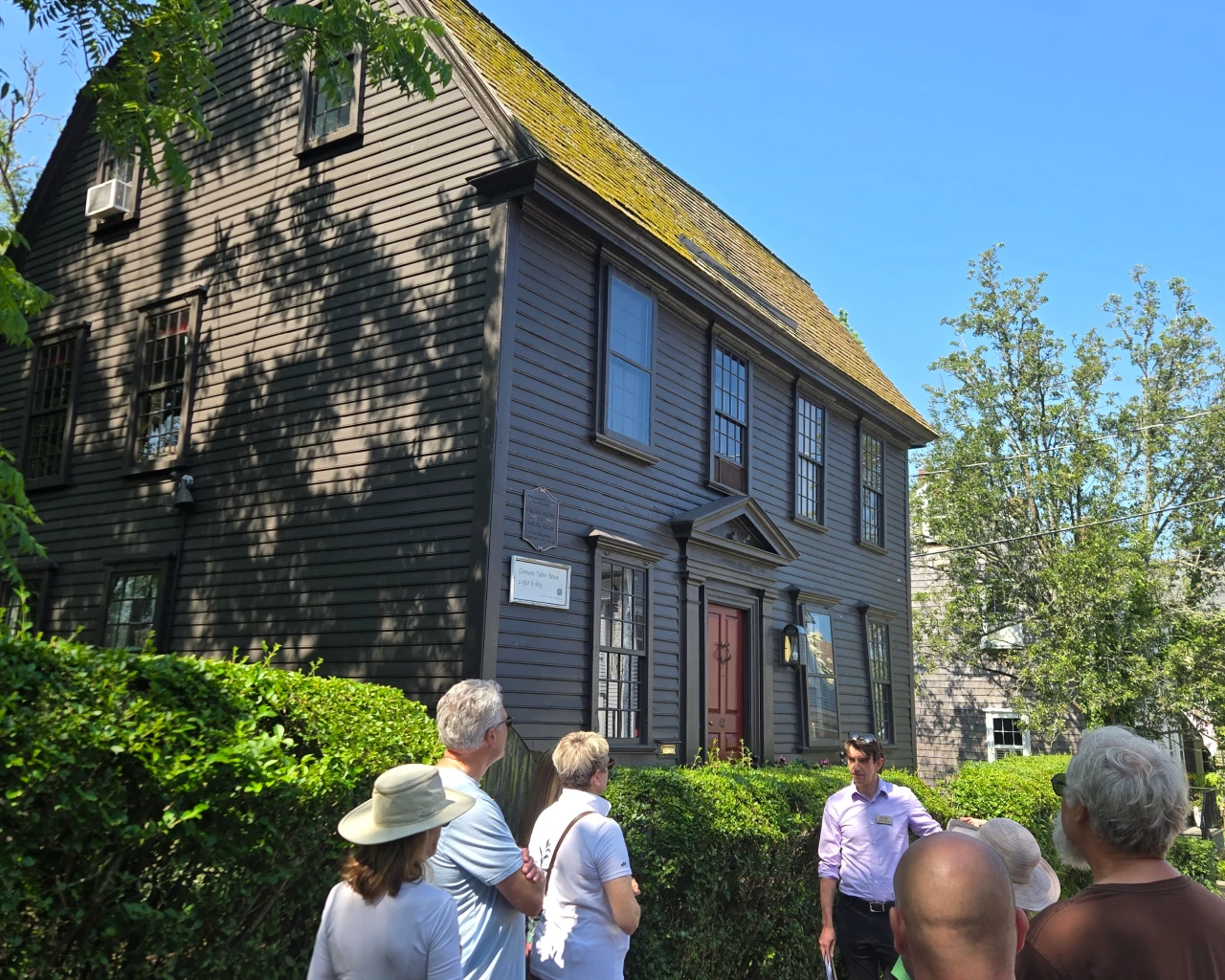 People outside on a walking tour, viewing a historic home